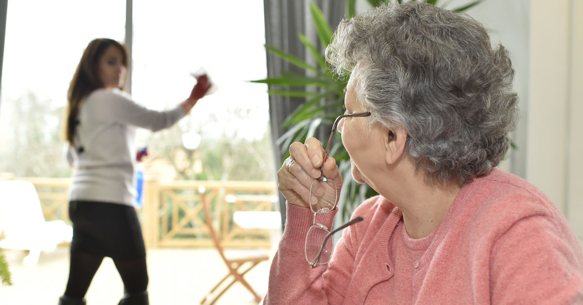 Aide Cleaning Windows For Senior Woman