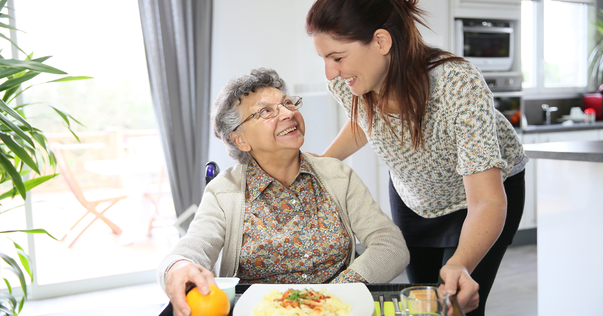 Daughter Providing Lunch For Mother. Caregiving By Family Members.