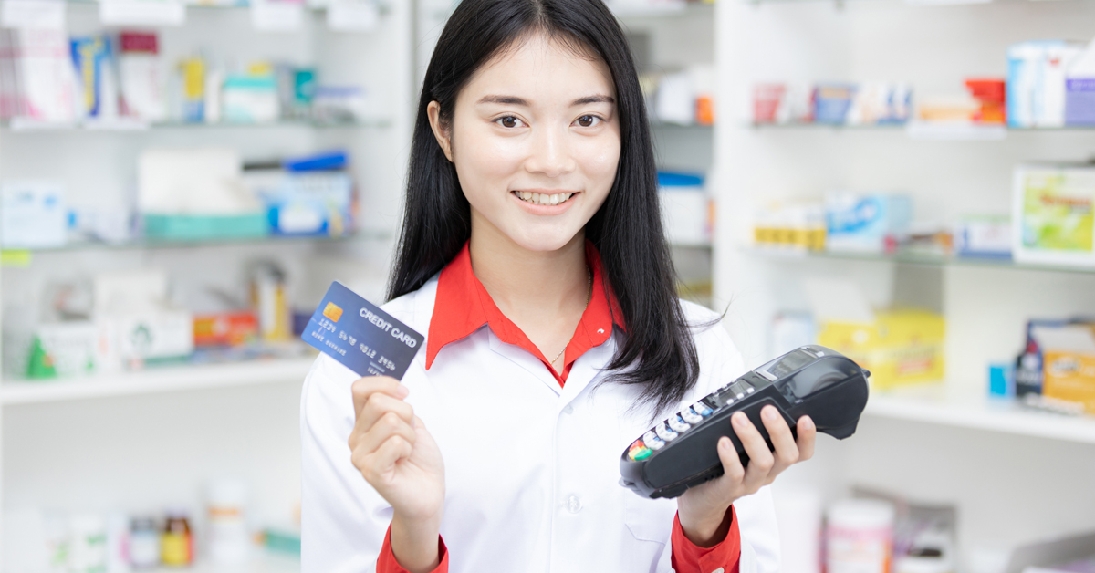 Female Pharmacist Holding A Credit Card And Credit Card Machine.