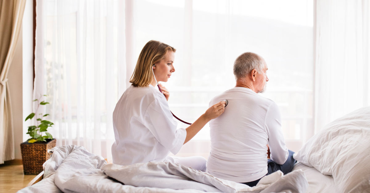 Nurse Checking Heart Rate Of Male Patient In His Home.