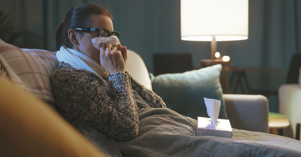 Lady Sick With The Flu On The Sofa With Blanket.