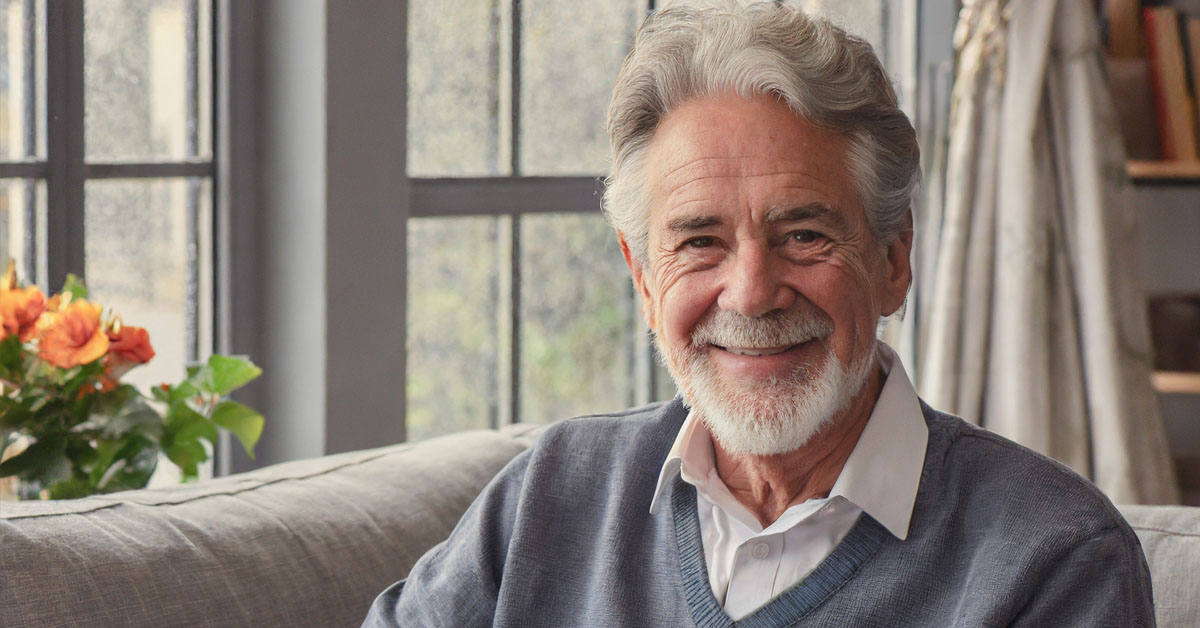 Smiling Senior Man Sitting On His Sofa In His Own Home.